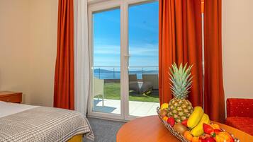 Una habitación de hotel con cama, una mesa de comedor con fruta y un balcón con vistas.