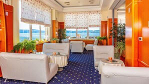 Una habitación con alfombra de estampado azul de estrellas, muebles blancos y ventanas amplias con cortinas florales.