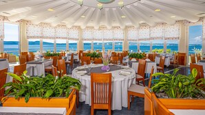 Un restaurante con mesas redondas, sillas de madera y plantas en macetas.