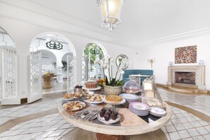 A buffet table with various desserts and pastries, surrounded by white arches and a chandelier. - Relais Villa Savarese (Sant'Agnello)