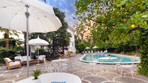 A poolside area with lounge chairs, umbrellas, and a pool. - Relais Villa Savarese (Sant'Agnello)