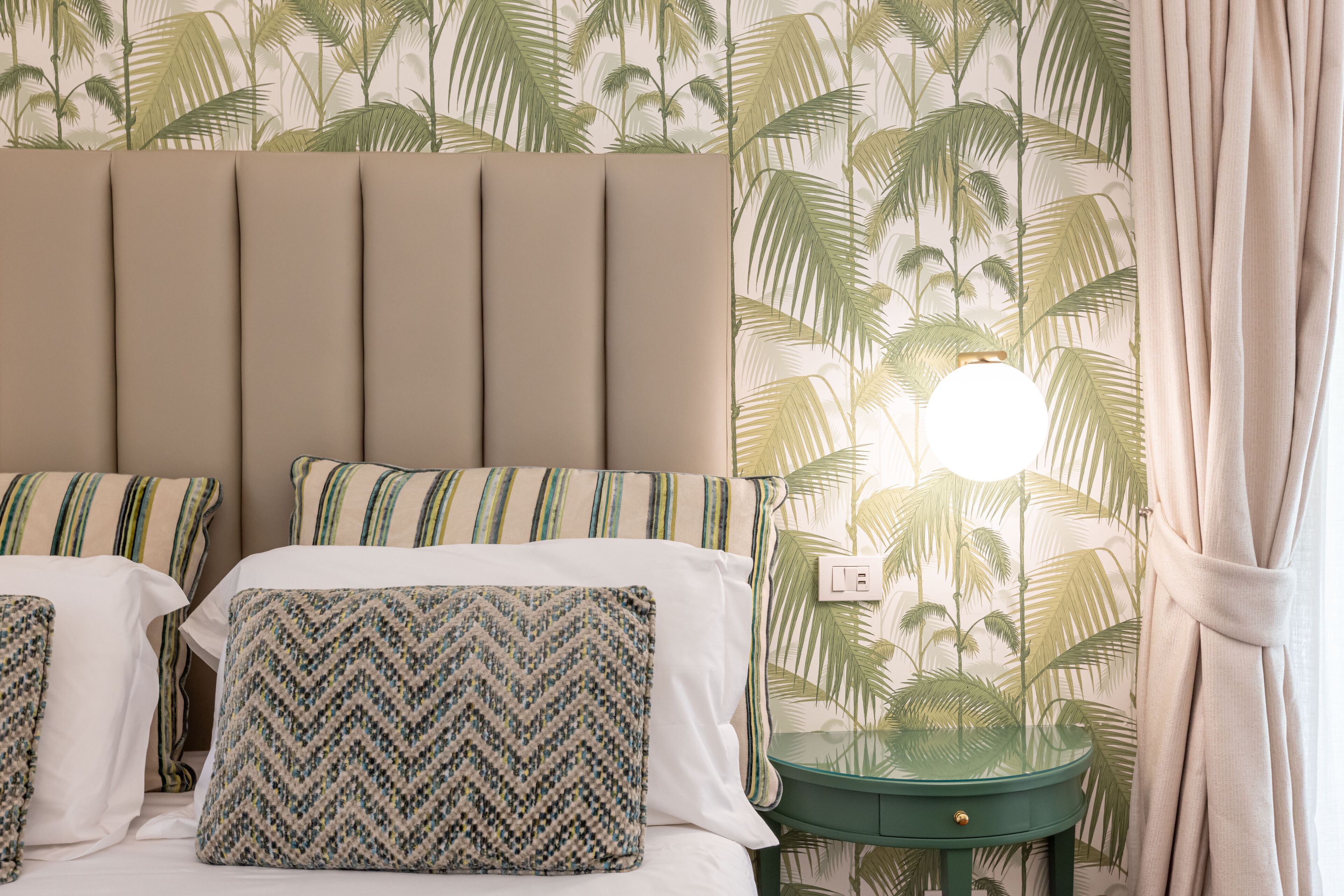 A bedroom with a bed, pillows, a nightstand, and a lamp.