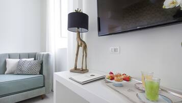 Una sala de estar moderna con un sofá, una mesa con una computadora portátil, una lámpara decorativa de jirafa y una bandeja con pasteles y un vaso de bebida verde.