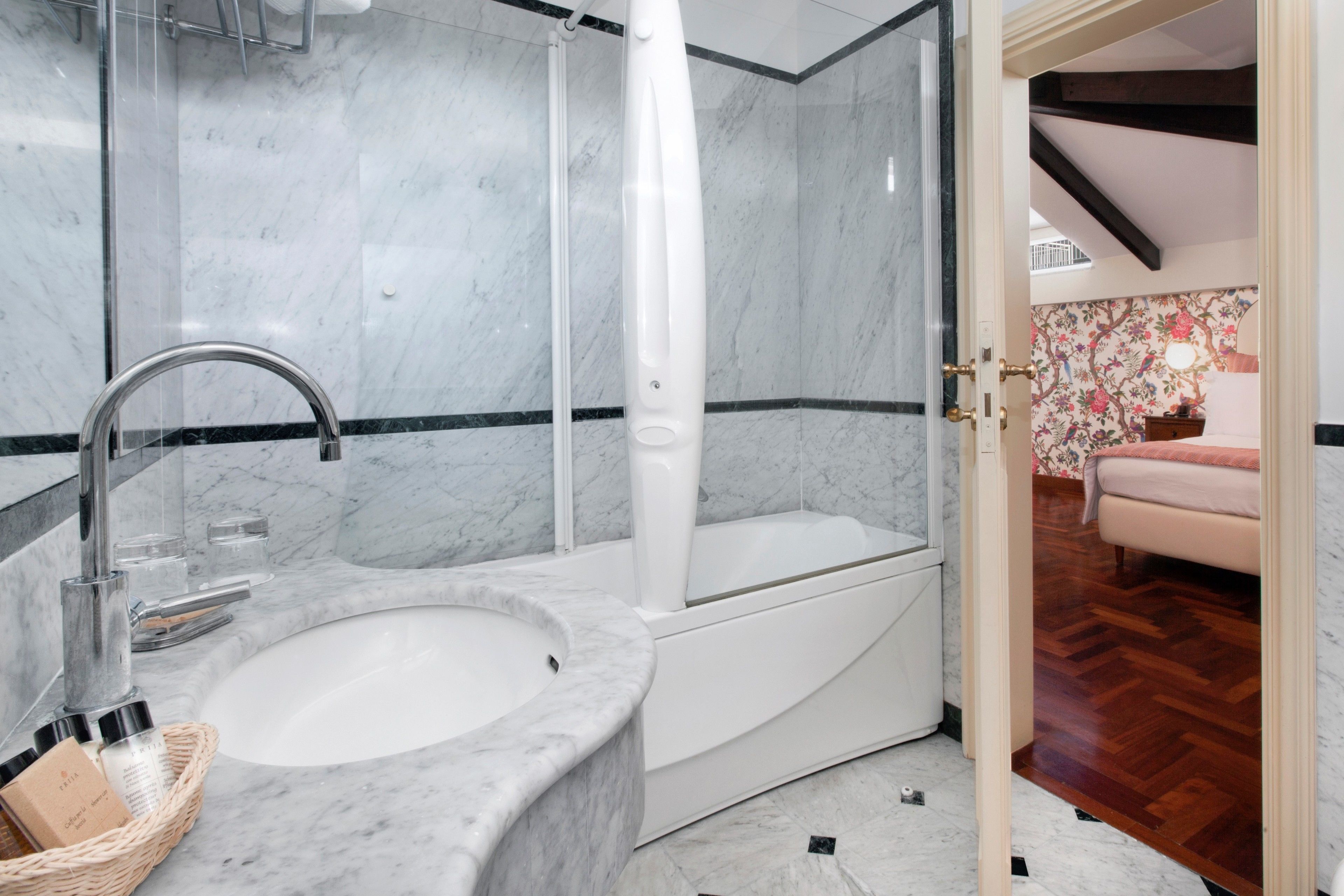 A modern bathroom with a marble sink, a bathtub, and a shower enclosure.