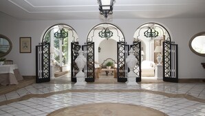 A spacious lobby with a tiled floor, a central round table, and a view into a bedroom through an open archway. - Relais Villa Savarese (Sant'Agnello)