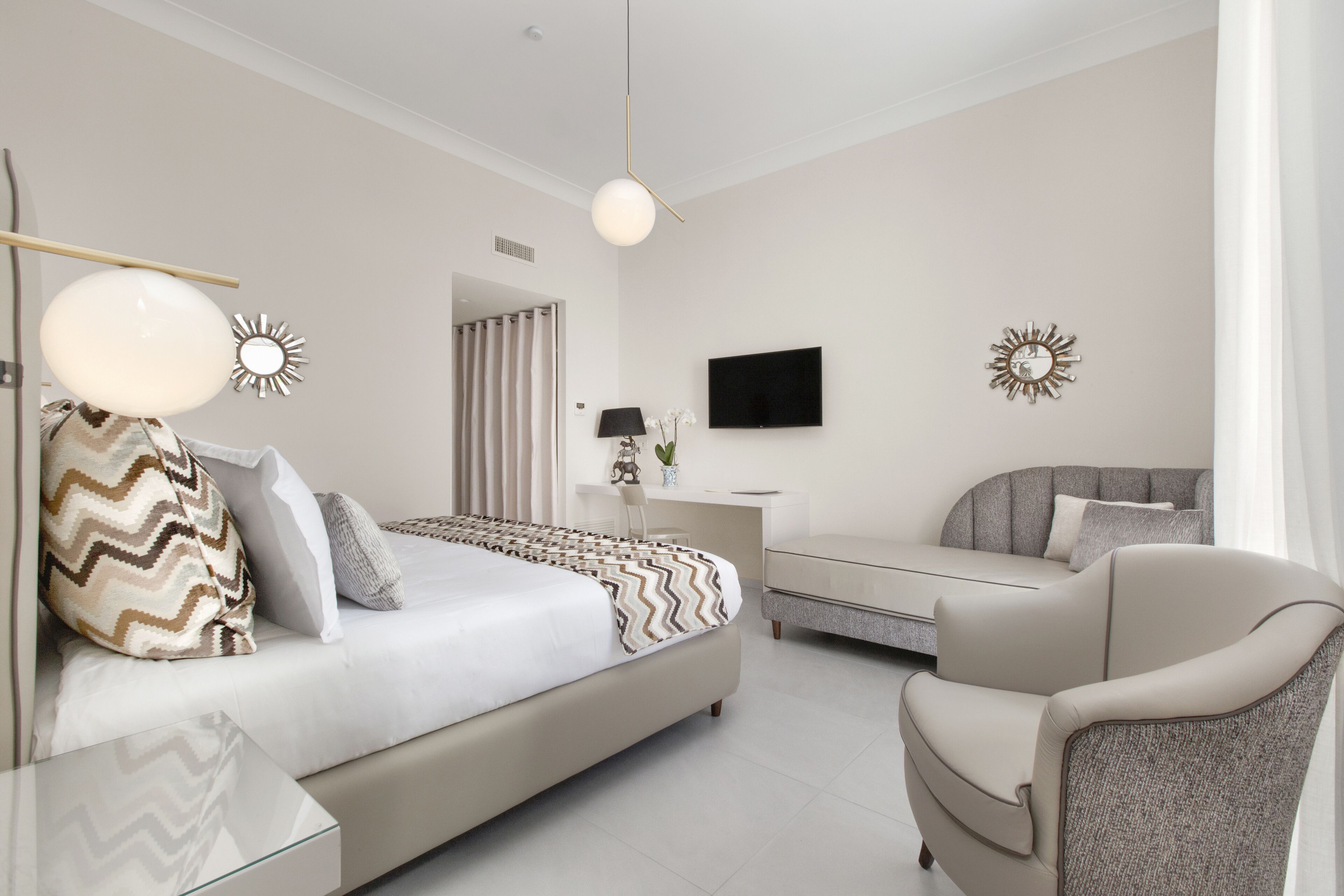 A modern bedroom with a bed, a desk, a chair, and a TV.