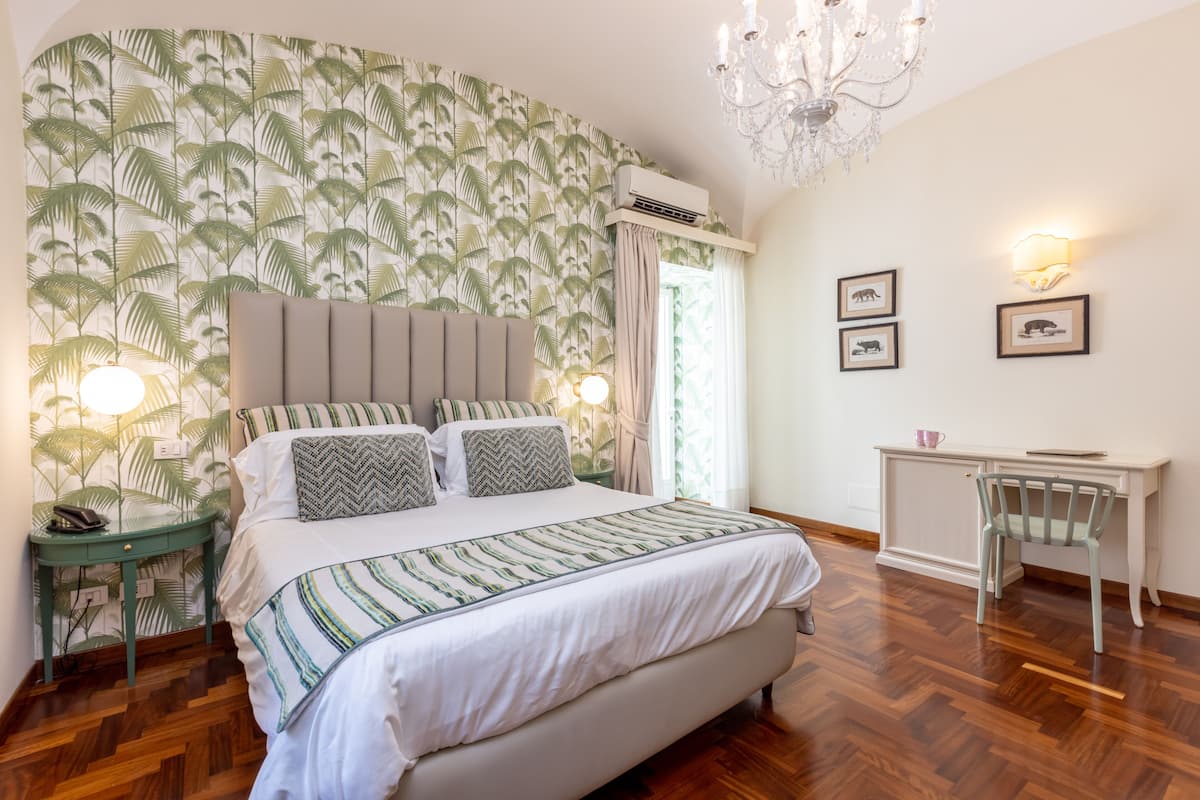 Un dormitorio con cama, mesita de noche, escritorio y silla.