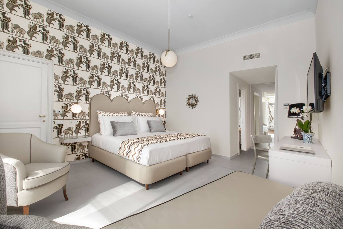Un dormitorio con una cama grande, una silla, un escritorio y una pared decorada con estampados de animales.