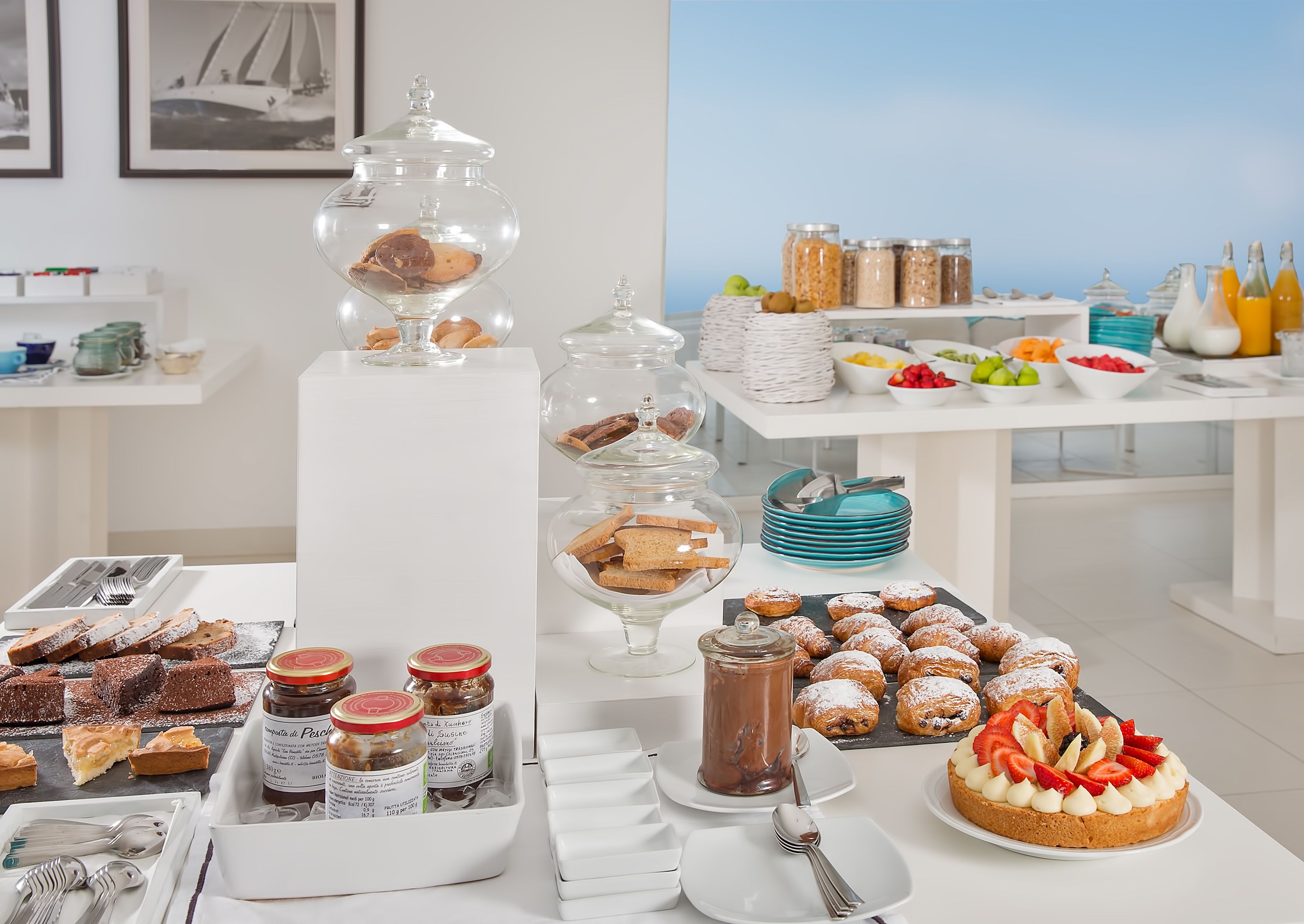 Een buffet met diverse etenswaren, waaronder gebak, fruit en toevoegingen.