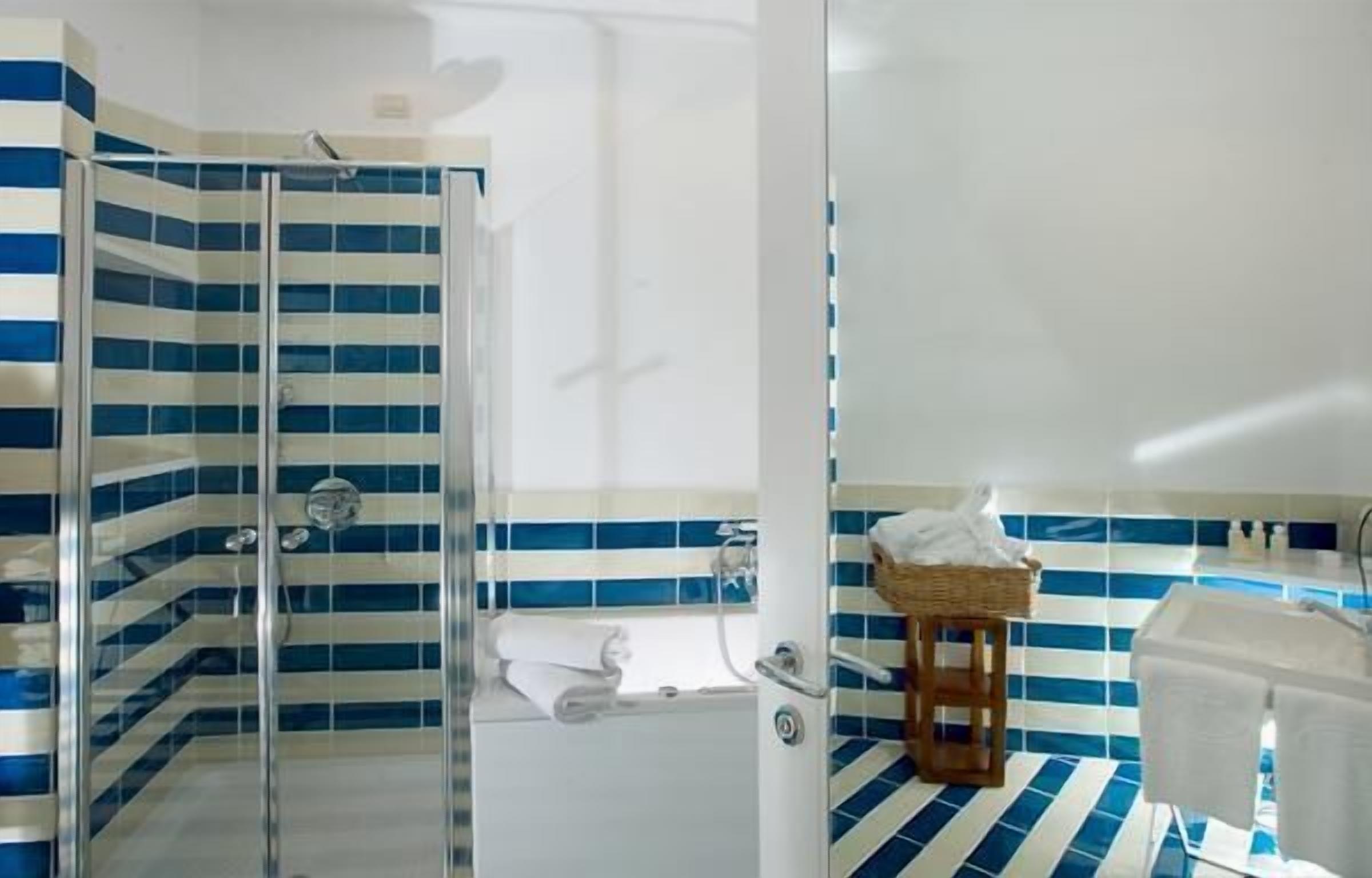 Un baño con cabina de ducha de vidrio, una bañera blanca y un revestimiento de azulejos a rayas.