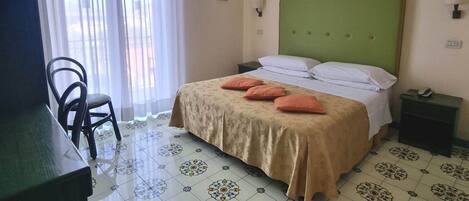 A hotel room with a bed, a desk, a chair, and a window with curtains.