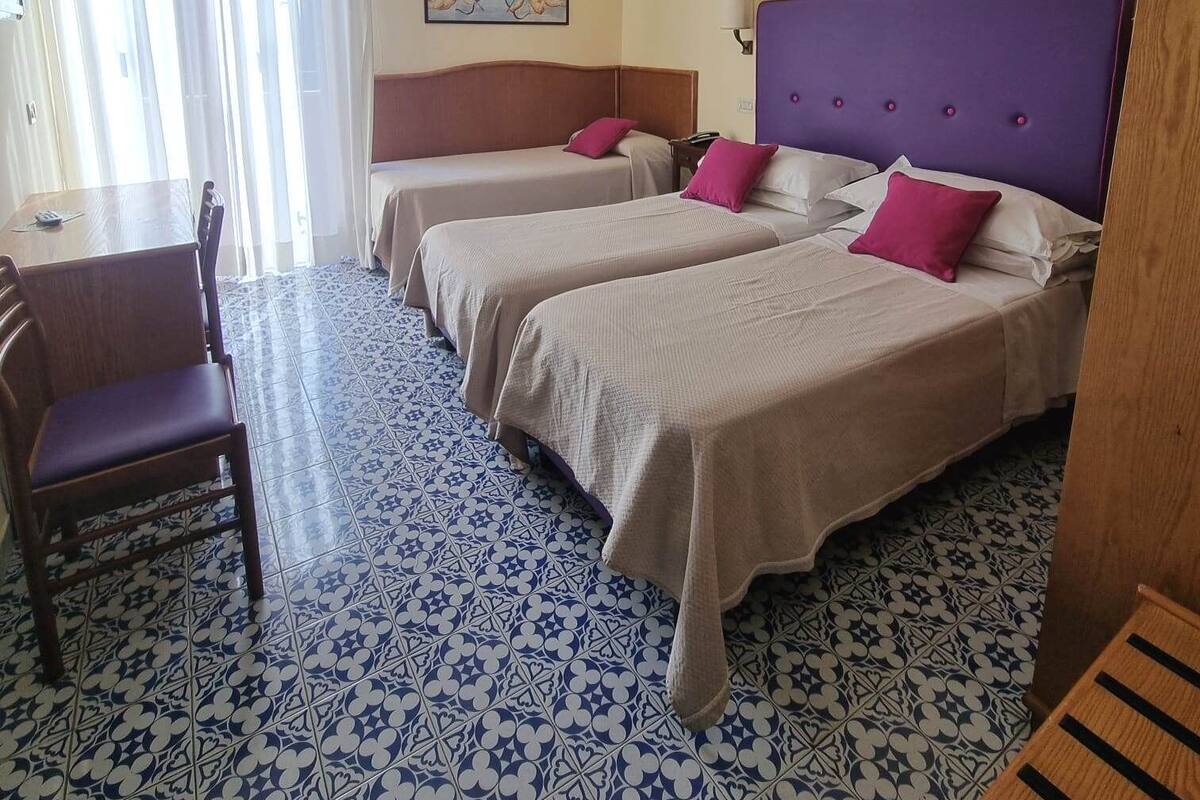 A hotel room with two beds, a desk, and a chair.