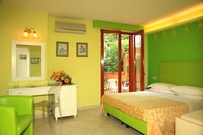 Un dormitorio con cama, escritorio, silla y ventana con vistas a vegetación.