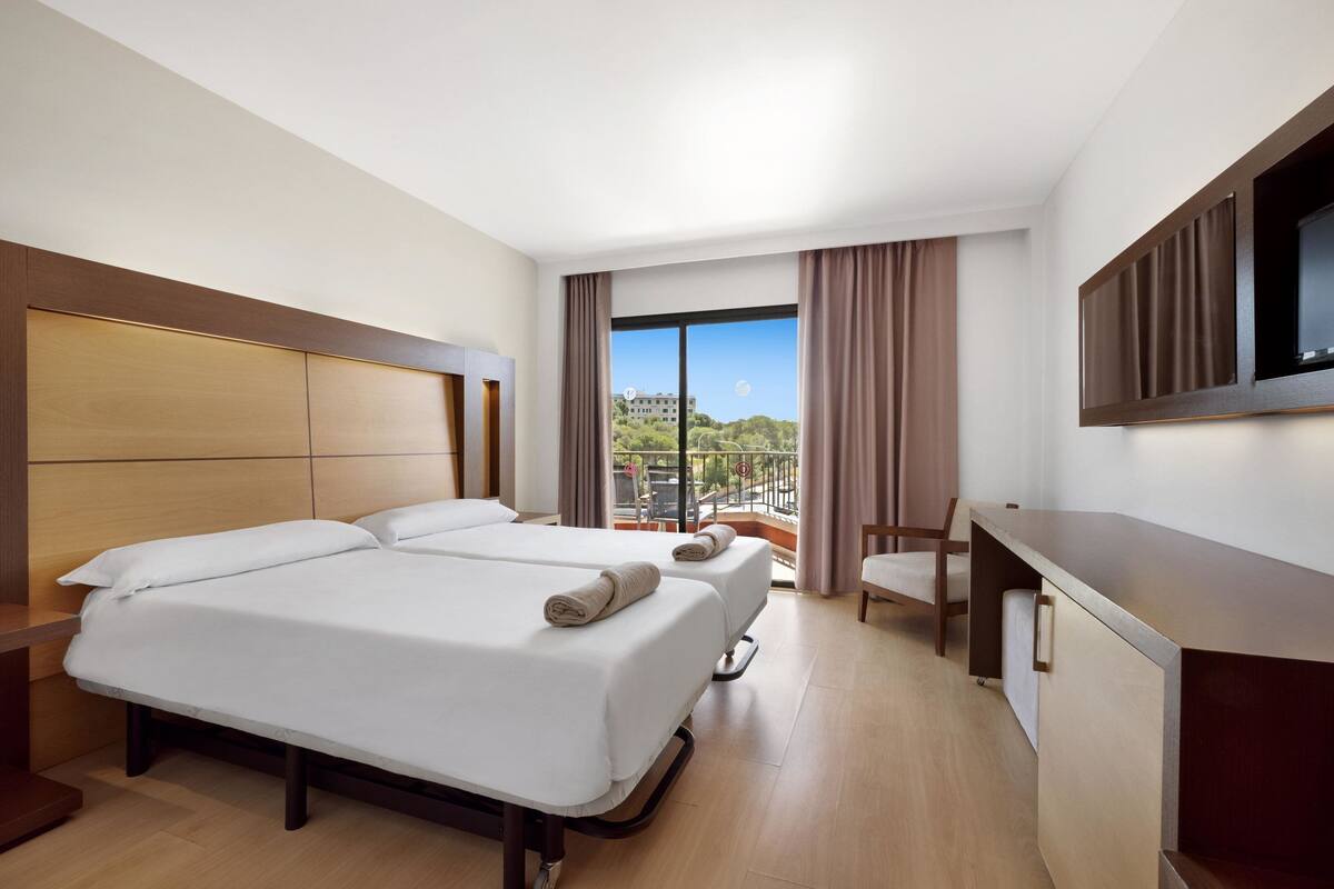 Una habitación de hotel con una cama grande, un escritorio, una silla y un televisor.