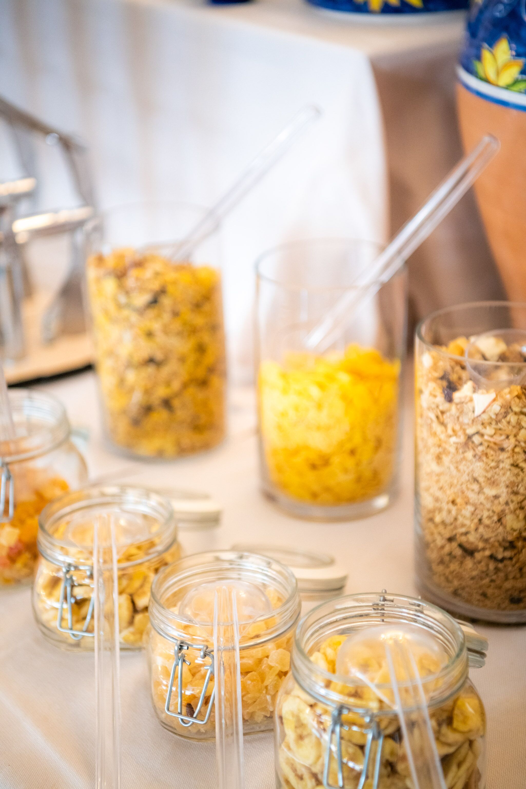 A buffet table with various food items in jars and glasses, including what appears to be cereal and fruit.