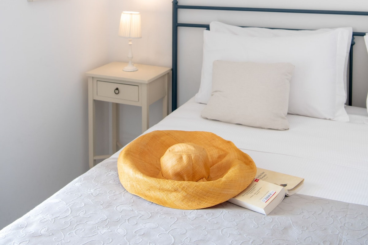 A neatly made bed with a white pillow, a bedside lamp, and a framed picture on the wall.