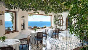 Un comedor con mesas redondas, sillas y plantas en macetas.
