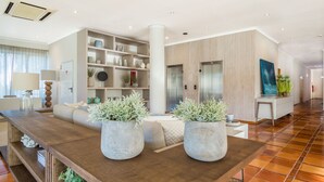A modern living room with a wooden coffee table, two large potted plants, a sofa, and a built-in bookshelf. - Mirachoro Carvoeiro (Lagoa)