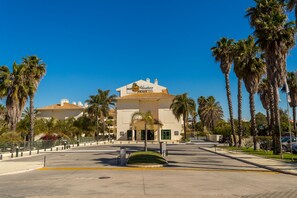 A hotel with a central entrance, palm trees, and a clear blue sky. - Mirachoro Carvoeiro (Lagoa)