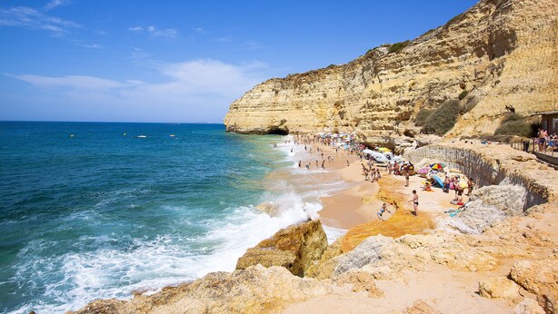 A beach with rocky cliffs, clear blue water, and people enjoying the seaside. - Mirachoro Carvoeiro (Lagoa)