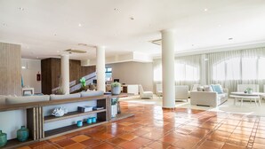 A spacious lobby with a tiled floor, a seating area with sofas and a coffee table, and a staircase in the background. - Mirachoro Carvoeiro (Lagoa)