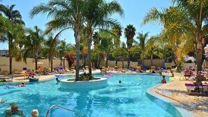 A swimming pool with multiple lanes, surrounded by palm trees and lounge chairs. - Mirachoro Carvoeiro (Lagoa)