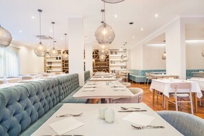 A modern restaurant with a long dining area, cushioned seating, and pendant lighting. - Mirachoro Carvoeiro (Lagoa)