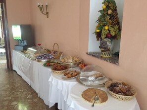 A buffet table with various food items and a decorative wall piece. - Hotel Mediterranee (Taormina)