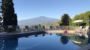 Une piscine avec des chaises longues et une vue sur la montagne.