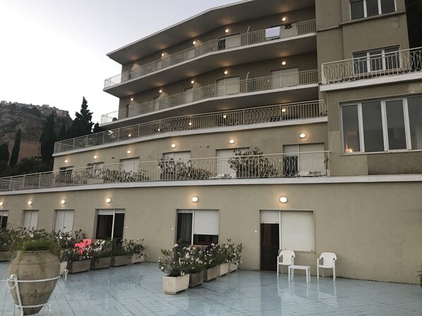 A multi-story building with balconies, potted plants, and outdoor seating. - Hotel Mediterranee (Taormina)