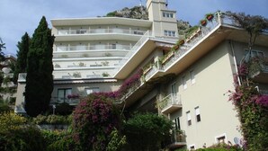 Un hôtel à plusieurs étages doté de balcons, entouré d’une végétation luxuriante et de plantes en fleurs.