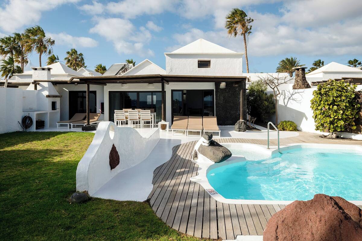 Eine moderne Villa mit Pool, Sitzgelegenheiten im Freien und einer Steinsäule.