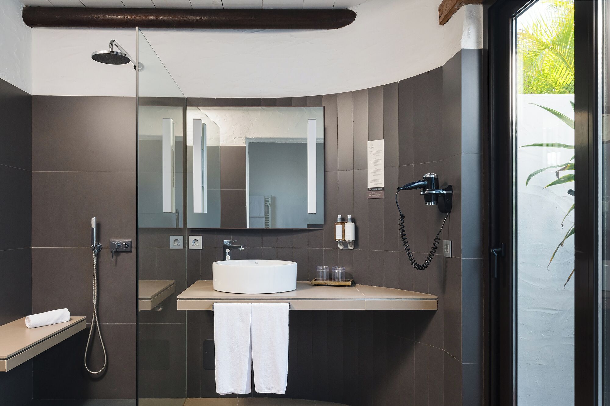 A modern bathroom with a glass shower enclosure, a white sink, and a large mirror.