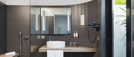 A modern bathroom with a glass shower enclosure, a white sink, and a large mirror.