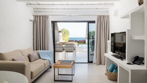 Un salon moderne avec un canapé, une table basse, un téléviseur et un balcon offrant une vue sur la mer.