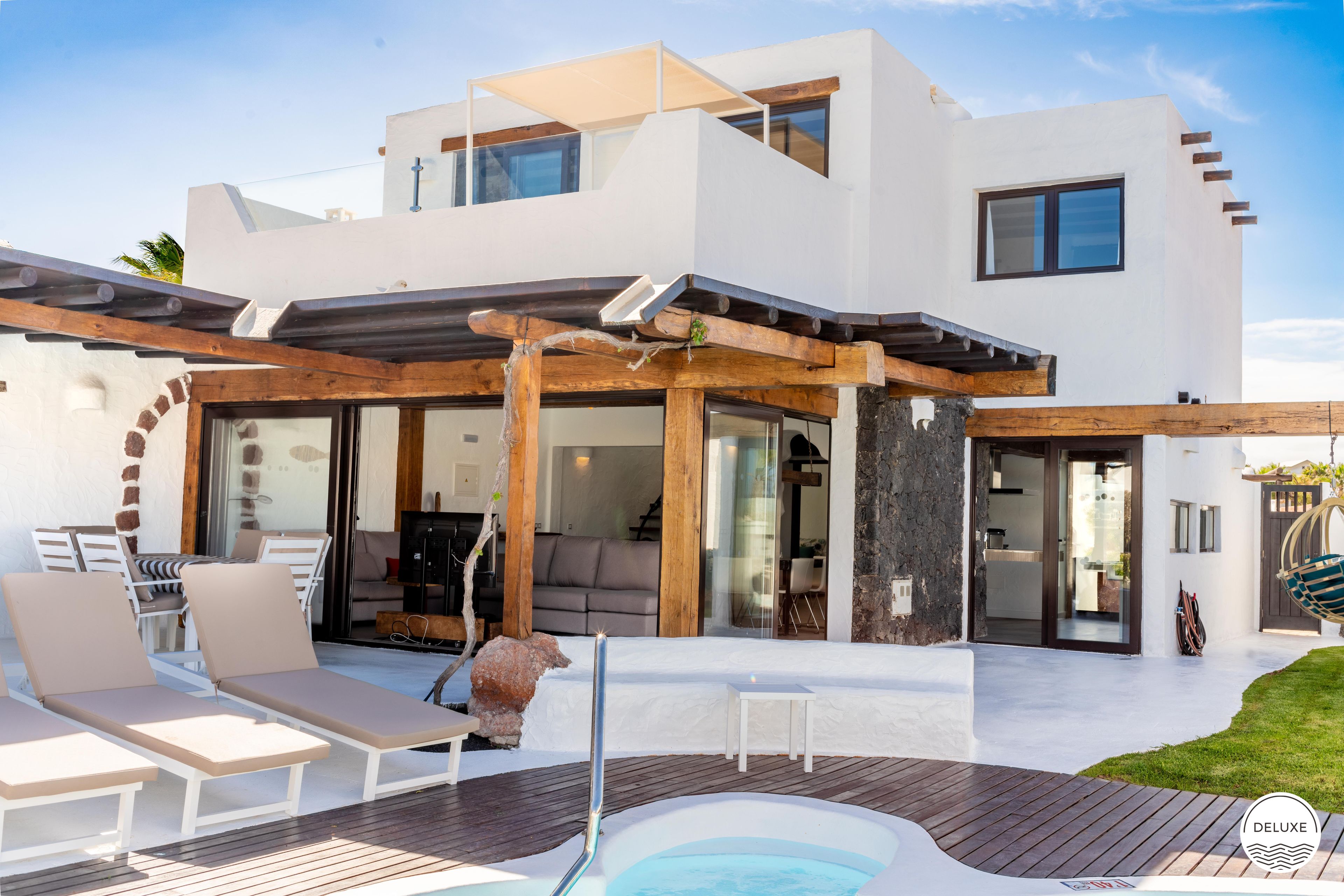 A modern house with a patio, outdoor seating, and a swimming pool.