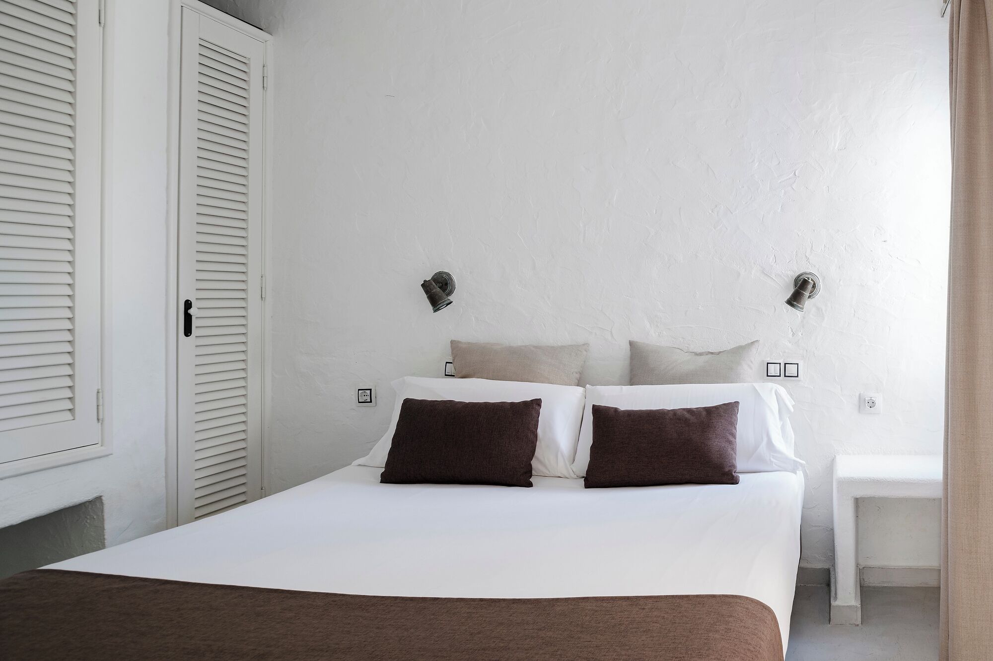 A bedroom with a bed, two bedside tables, and a window.