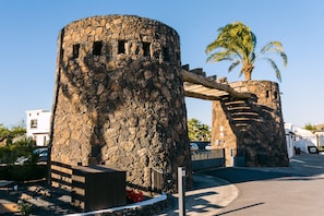 Una torre de piedra con un pasillo de madera que lleva a una palmera.