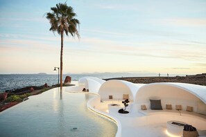 Ein modernes Resort mit Pool, weißer Architektur und einer Palme.