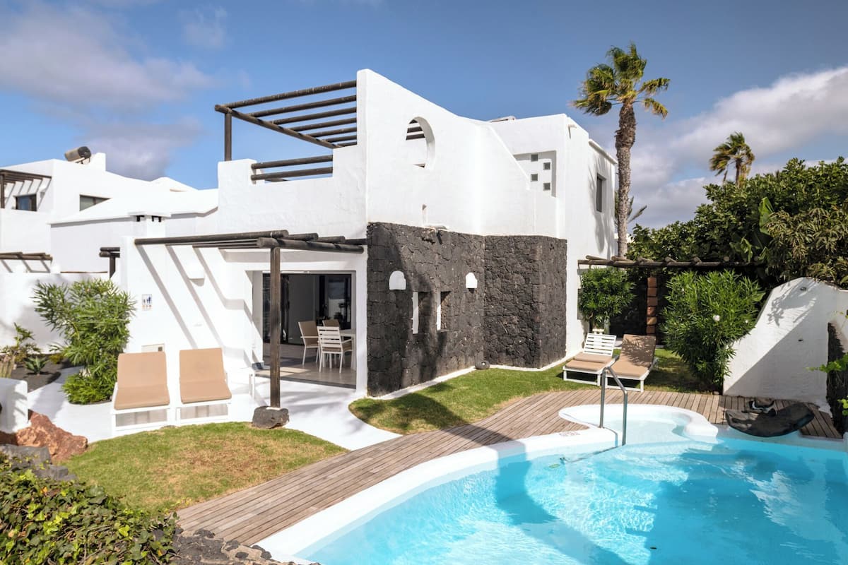 Ein modernes Haus mit Swimmingpool, Sitzgelegenheit im Freien und einer Pergola.