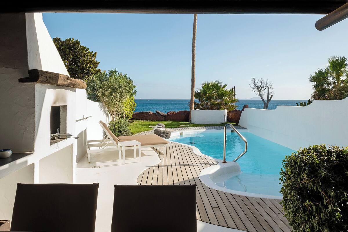 Ein Poolbereich mit Meerblick, Liegestühlen und einer Holzterrasse.