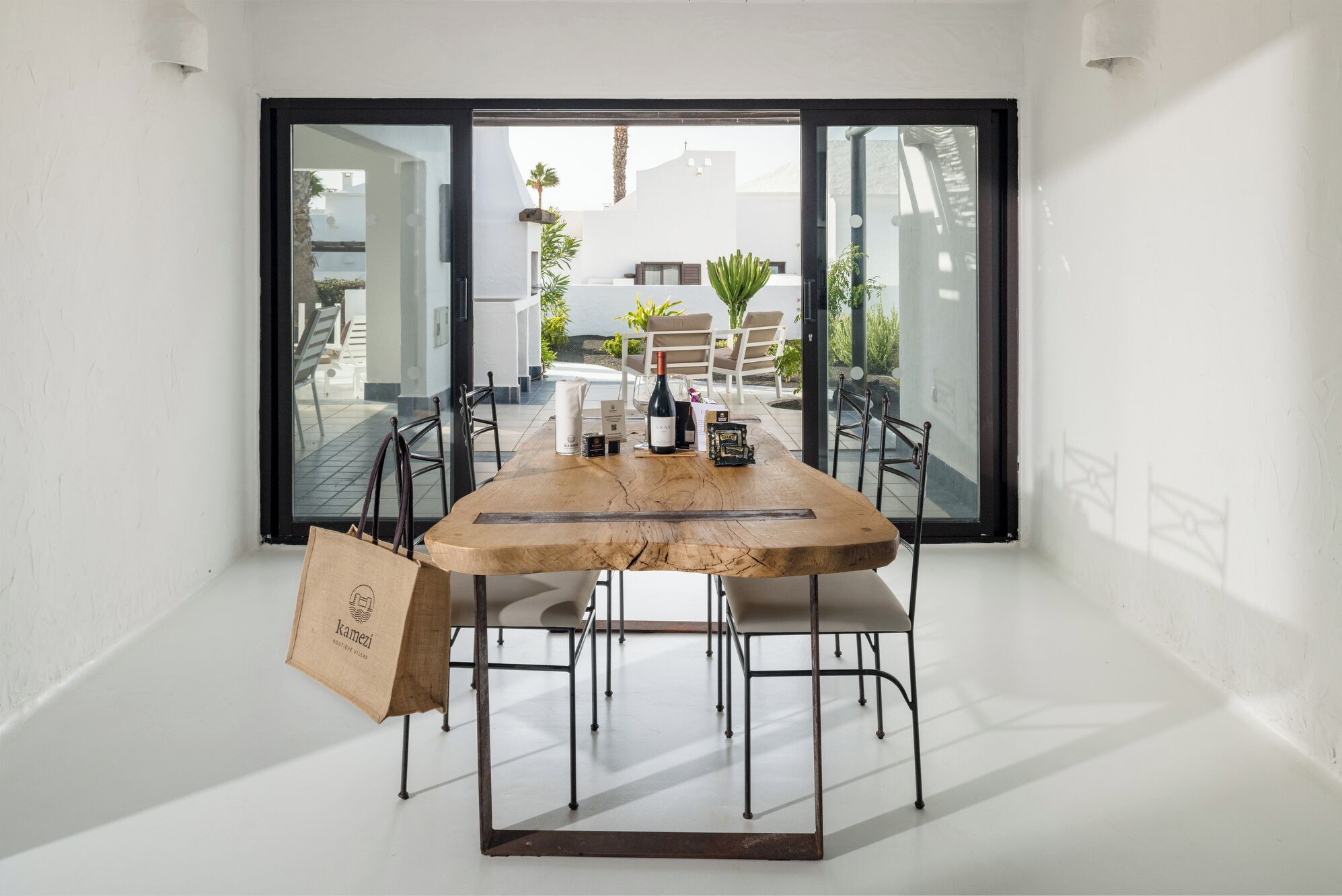 Ein moderner Essbereich mit einem Holztisch, Metallstühlen und einer großen Glasdoor, die zu einer Terrass führt.