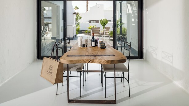 Een moderne eetruimte met een houten tafel, metalen stoelen en een grote glazen deur die uitkomt op een terras.