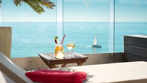 Un balcón con vista al mar, una mesa con bebidas y una toalla roja.