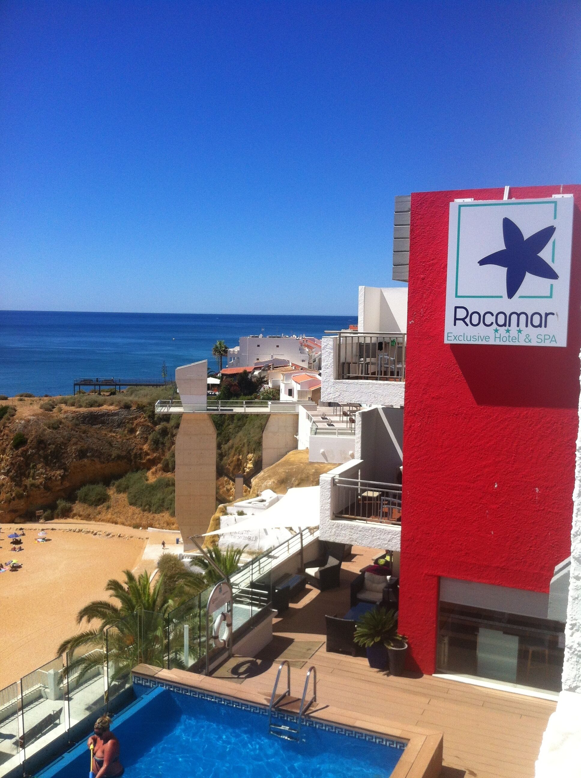 A hotel with a pool, a view of the beach, and a sign for Rocamar.