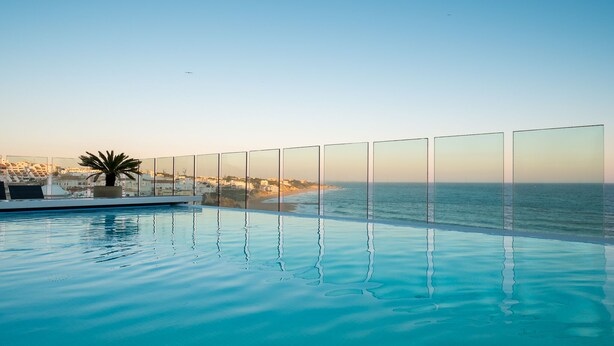 Una piscina infinita con vistas despejadas al océano y a la costa distante.