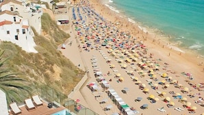 Un complejo turístico en la playa con piscina, sombrillas y vista al mar.
