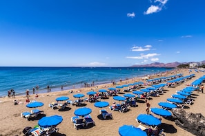 A beach with rows of blue umbrellas and sun loungers.
