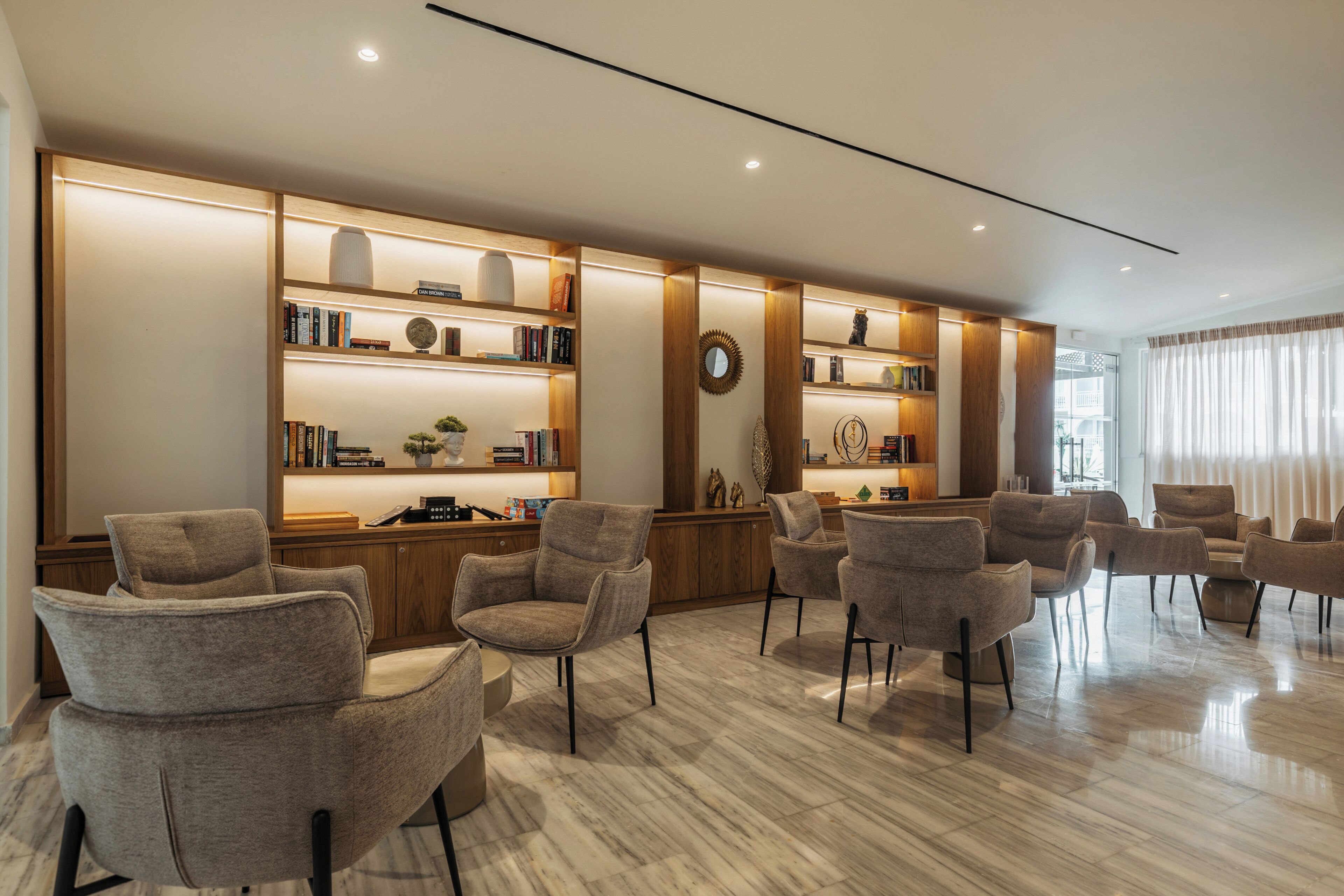 A modern interior with a marble floor, multiple seating areas, and built-in bookshelves.