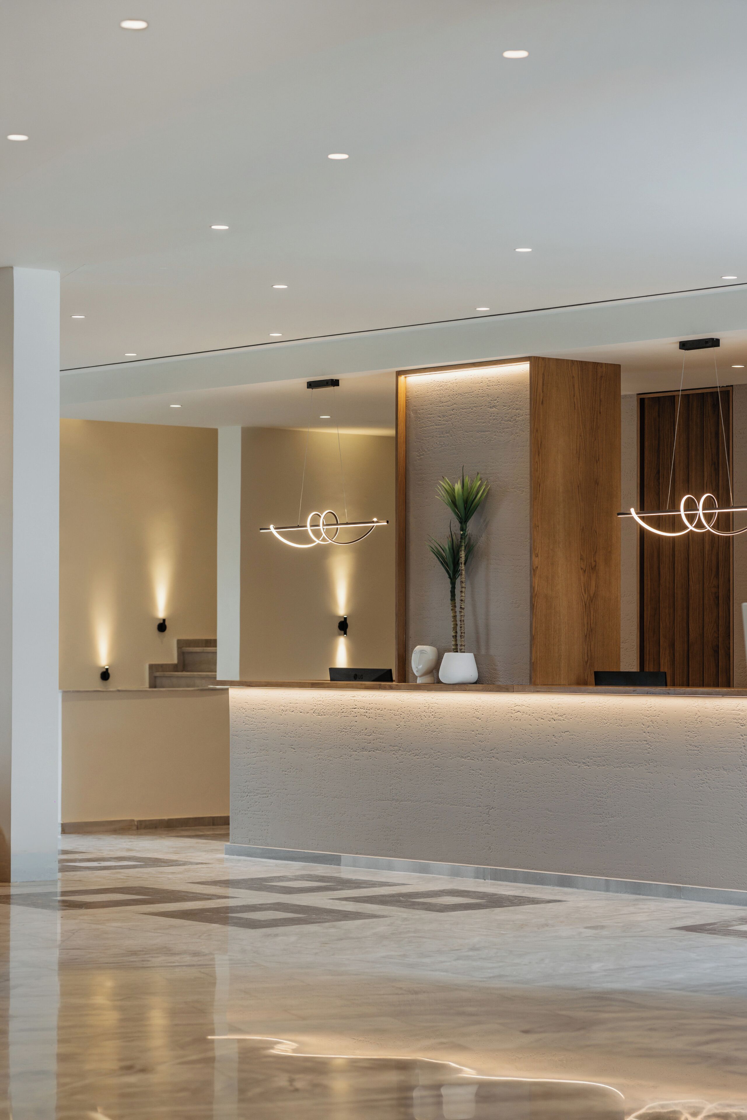 Una zona de recepción moderna con piso pulido, un revestimiento de pared de madera y una planta en maceta.